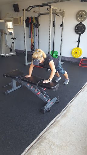 A woman is doing push ups on a bench in a gym.