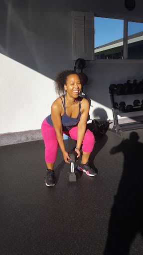 A woman is squatting with a dumbbell in a gym.