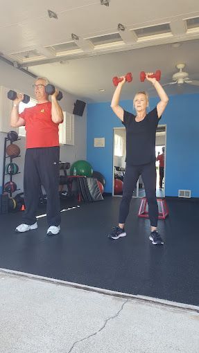 A man and a woman are lifting dumbbells in a gym.