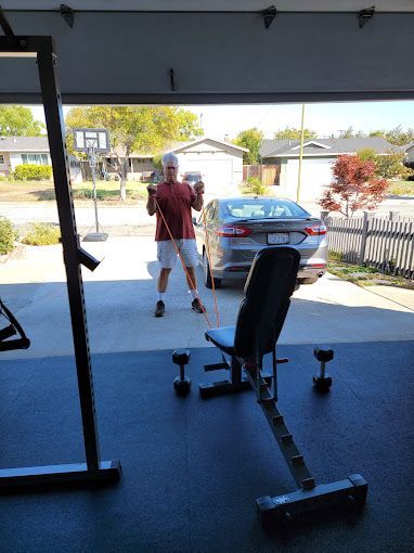 A man is standing in a garage holding a resistance band.