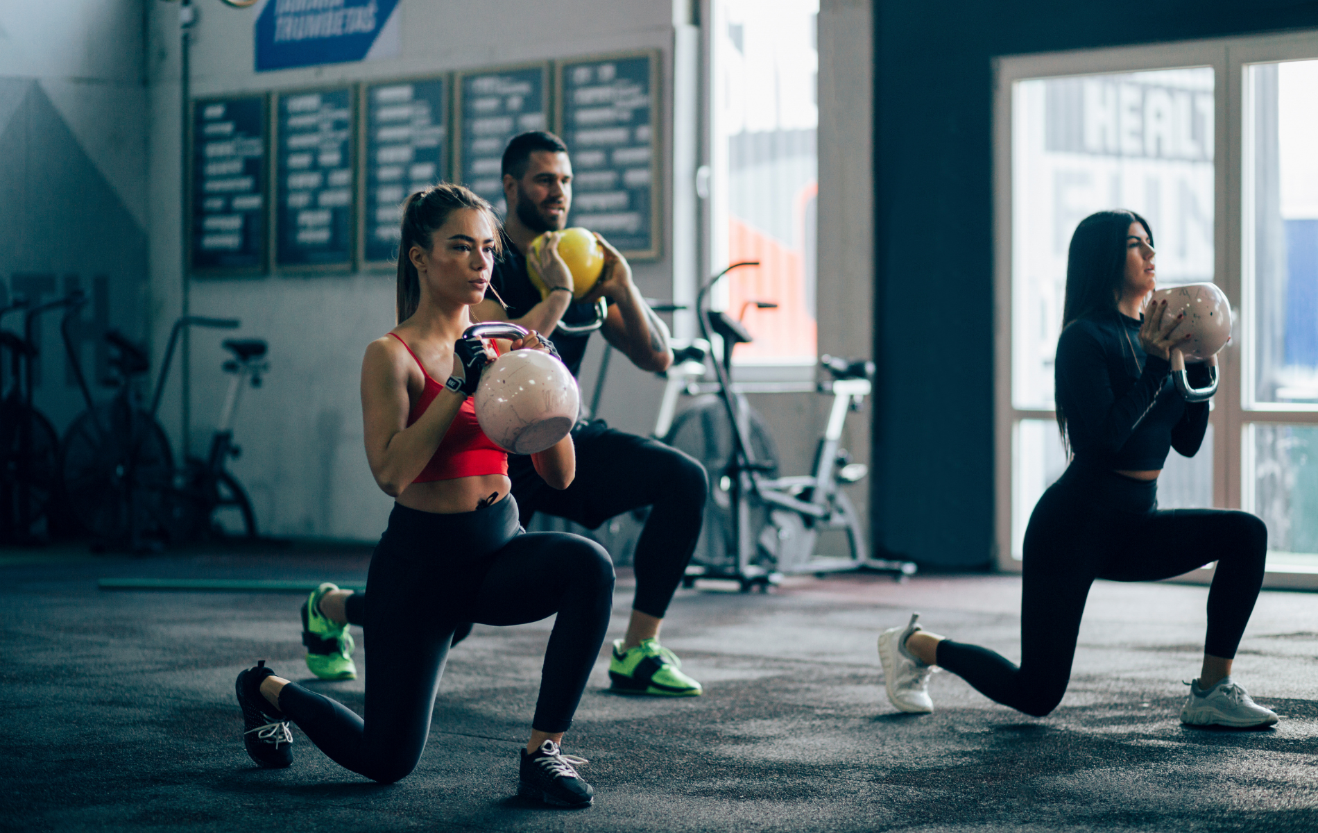 A group of people are doing lunges in a gym.