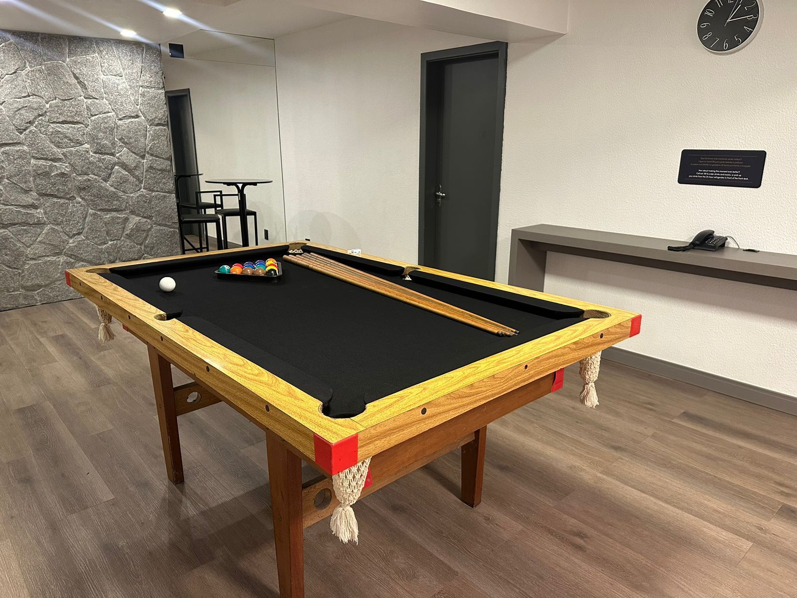 Uma mesa de sinuca em uma sala com um relógio na parede