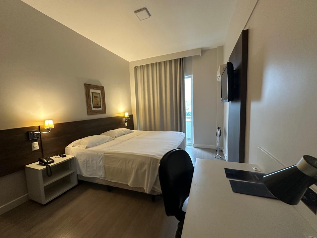 A hotel room with a king size bed and a desk.