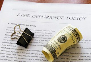 one hundred dollar bill rolled up on life insurance document