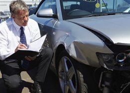 claims agent inspecting vehicle after auto accident