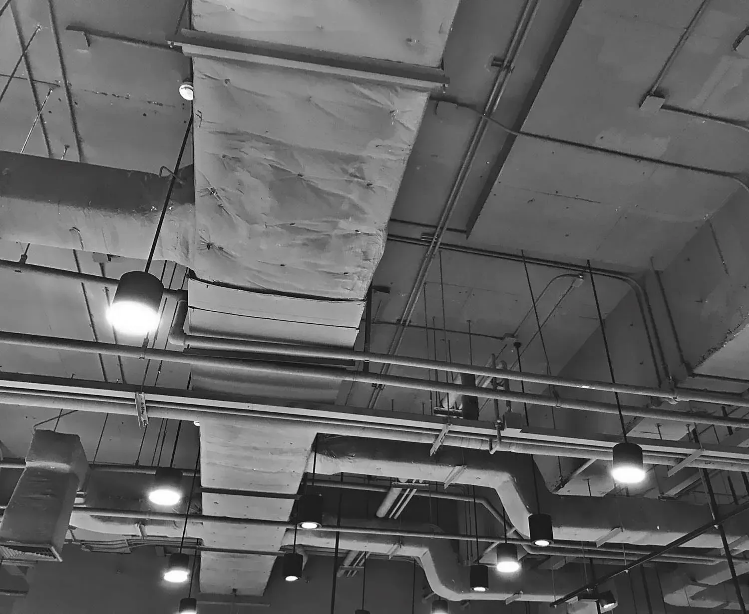 A Black and White Ceiling With Pipes and Lights — DMC Electrical & Air Cooling Pty Ltd in Townsville City, QLD
