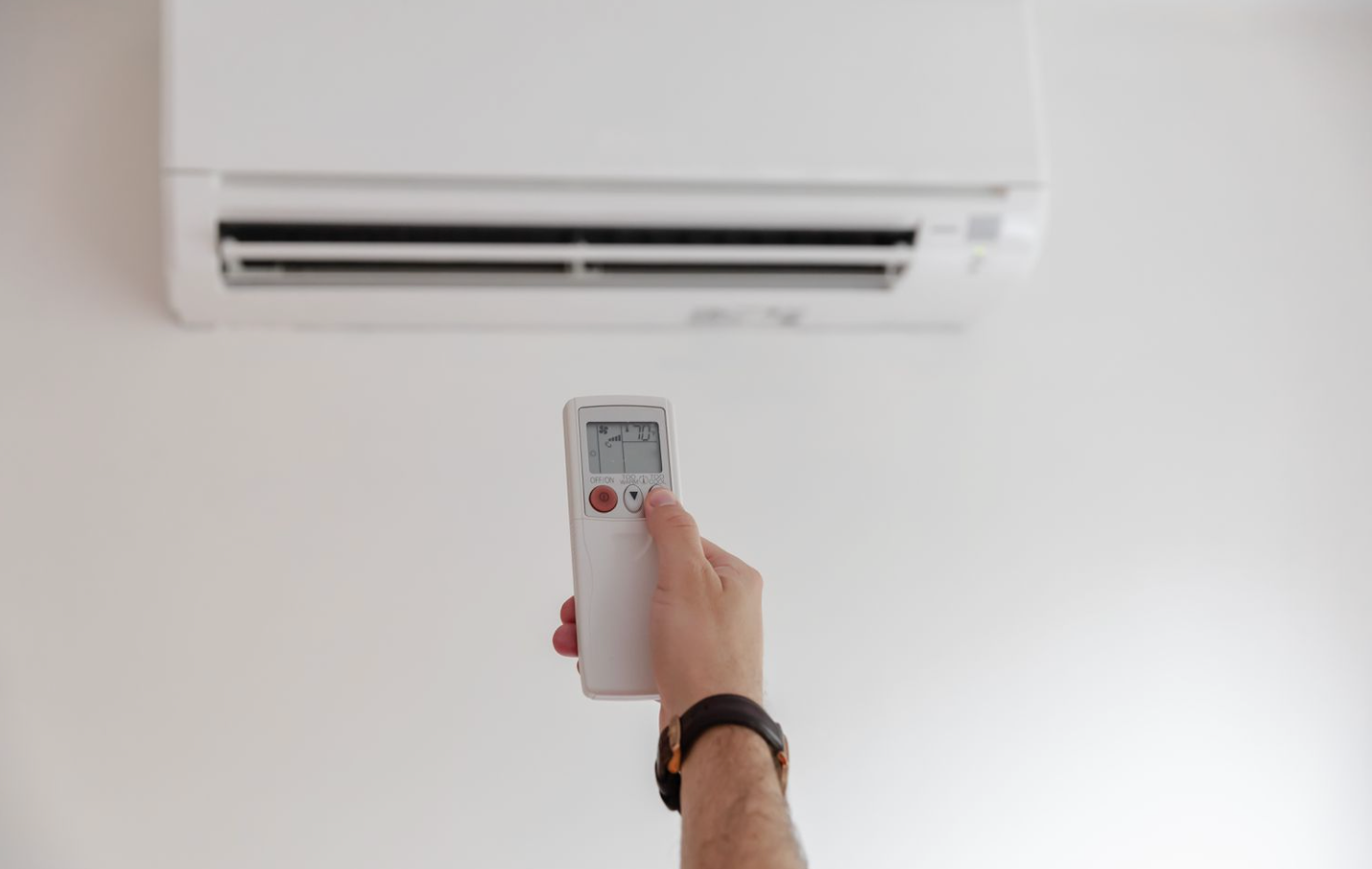 hand using remote to operate split system air conditioner in a Townsville home