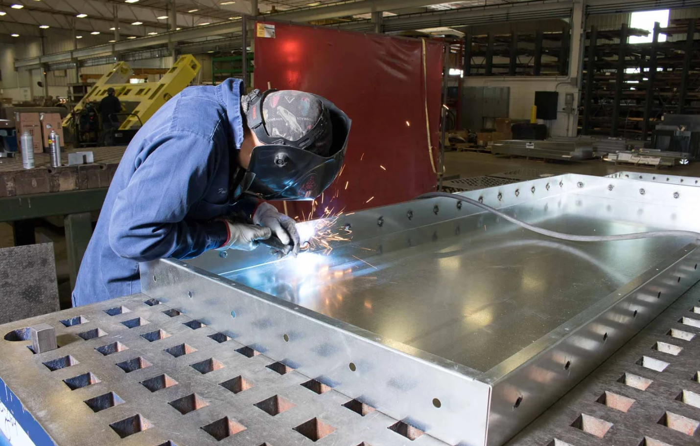 A Man is Welding a Piece of Metal in a Factory - DMC Electrical & Air Cooling Pty Ltd in Ayr, QLD