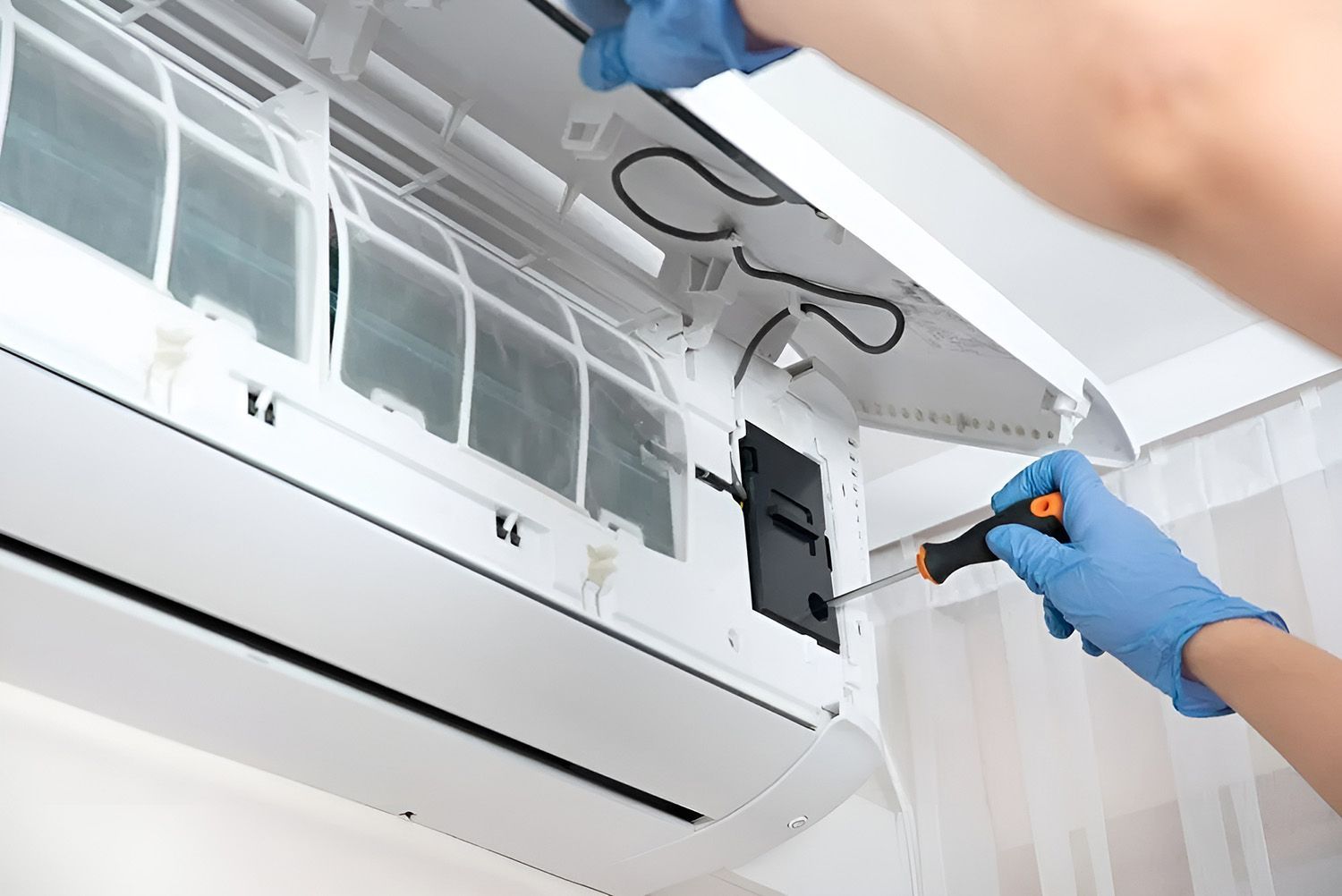 Person Wearing Blue Gloves Servicing a White Air Conditioner