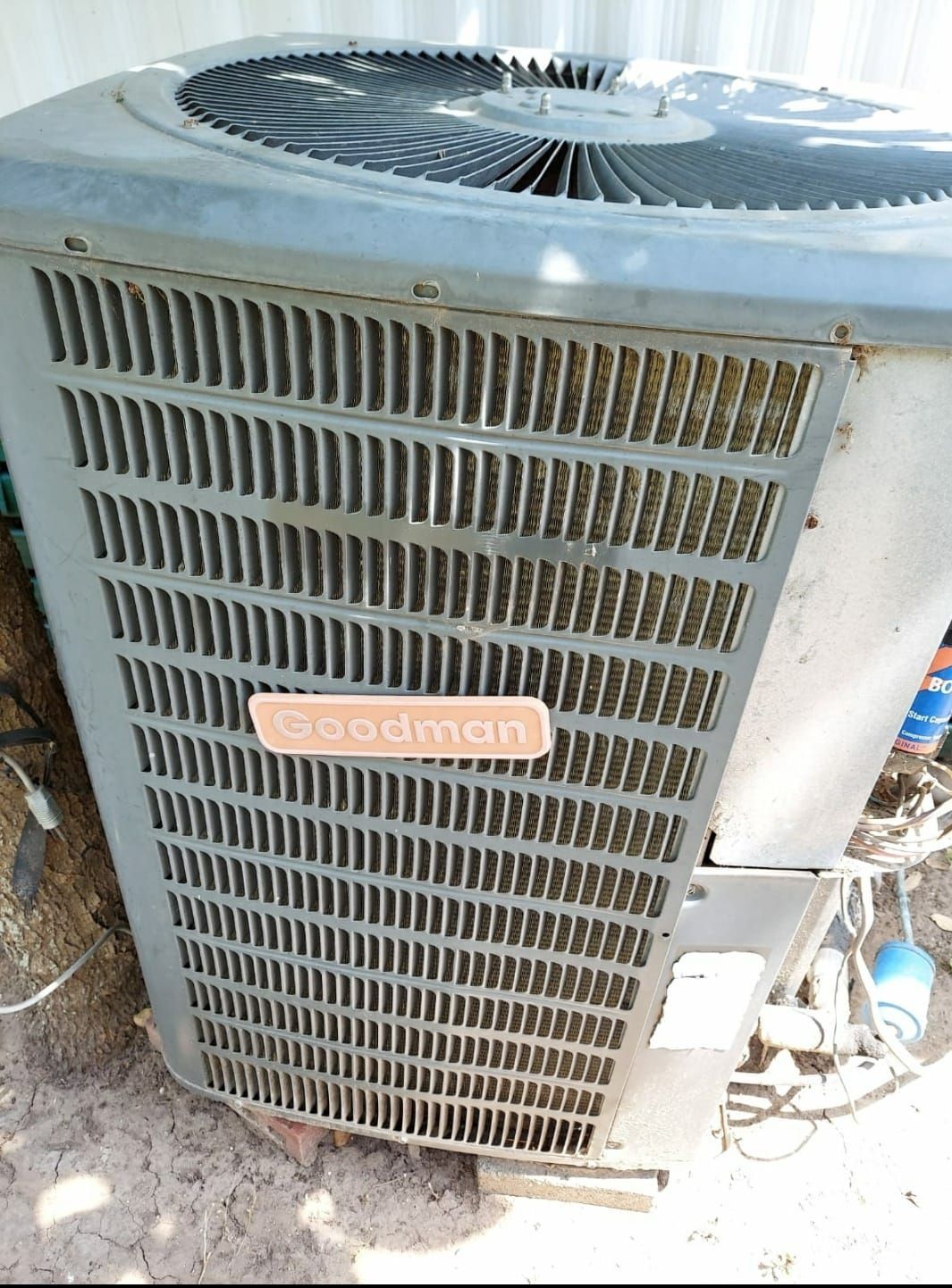 A coleman air conditioner is sitting on the ground outside.
