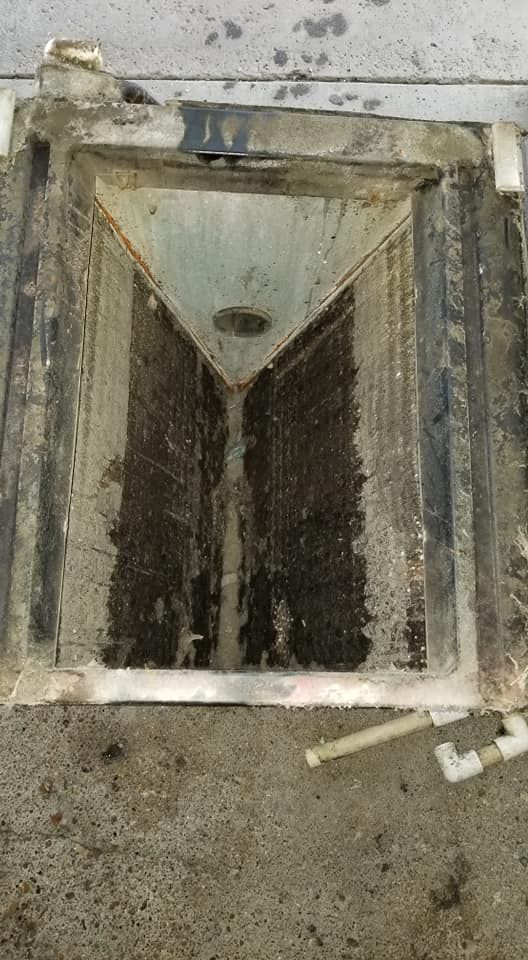 A dirty manhole cover is sitting on a concrete floor.