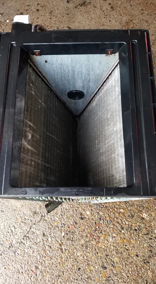 A dirty air conditioner is sitting on a concrete floor.
