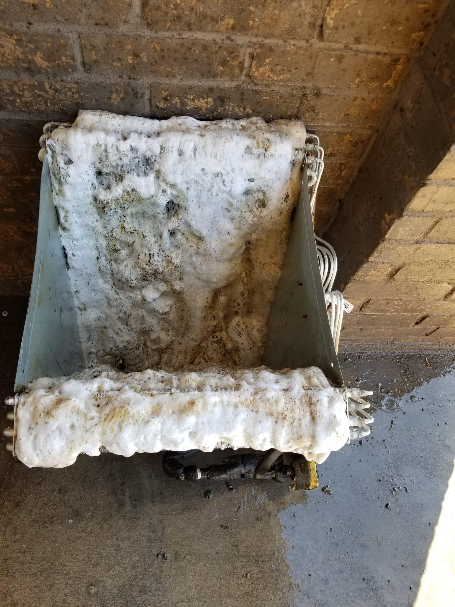 A piece of foam is sitting on the ground next to a brick wall.