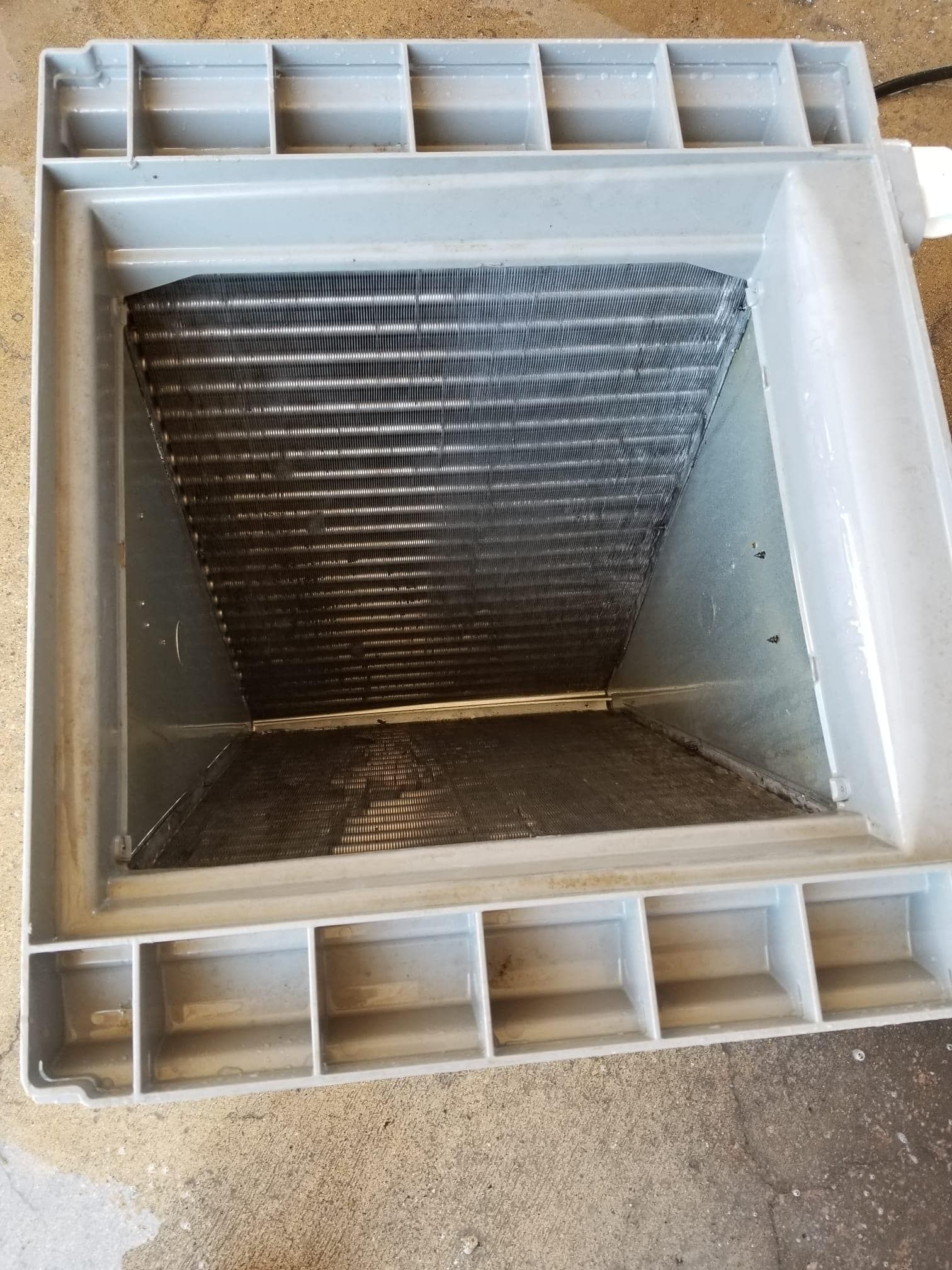The inside of a plastic box with a metal grille.