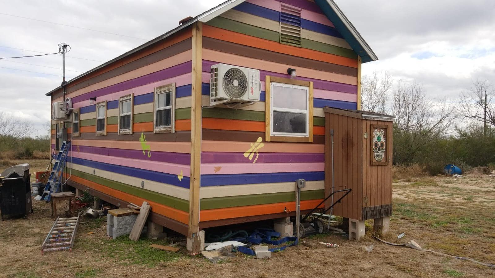A colorful house with a lot of windows is sitting in the middle of a field.