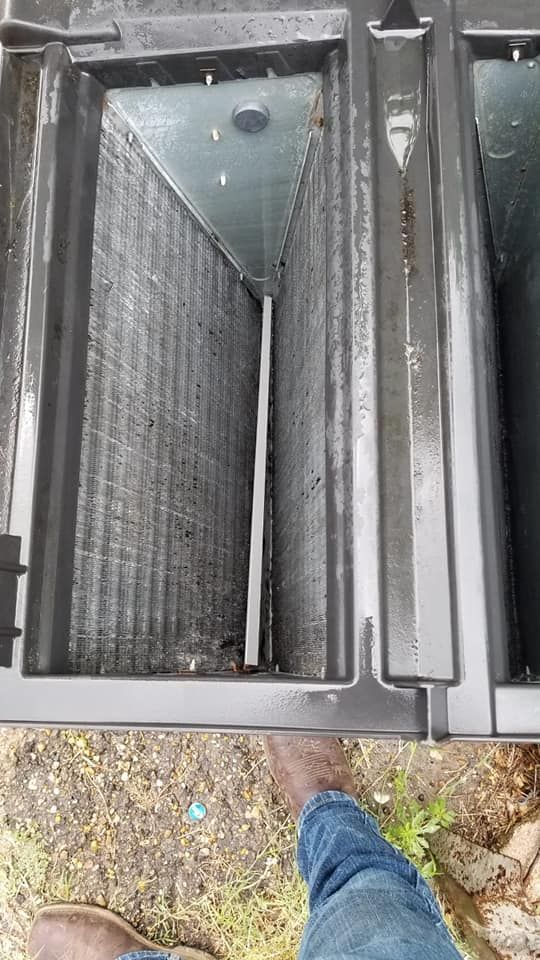 A person is standing next to a dirty air conditioner.