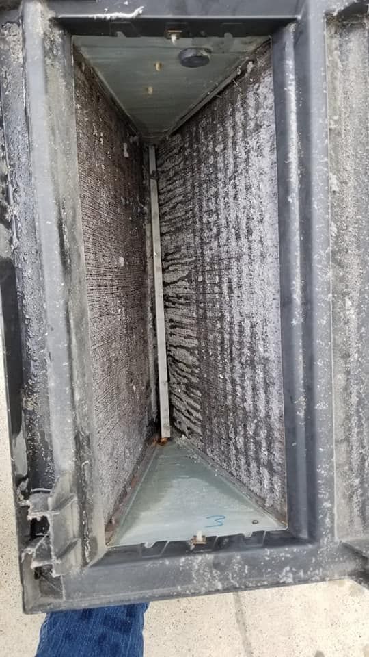 A person is standing next to a dirty air conditioner.