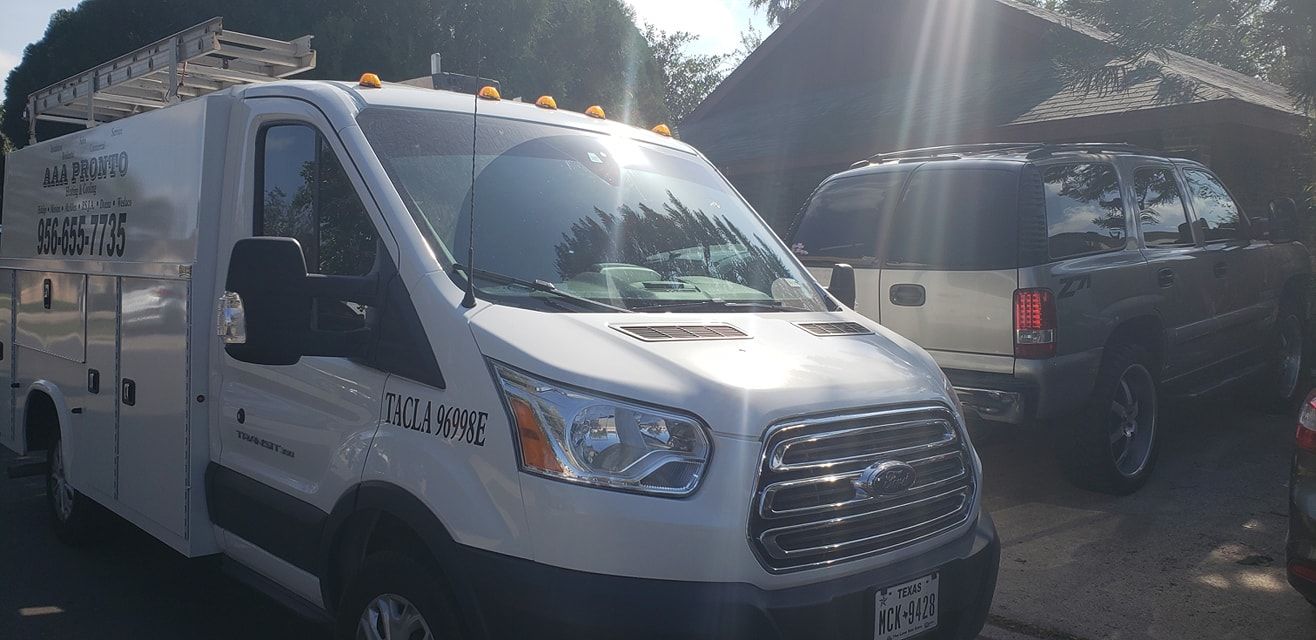 A white van is parked in a parking lot next to a truck.