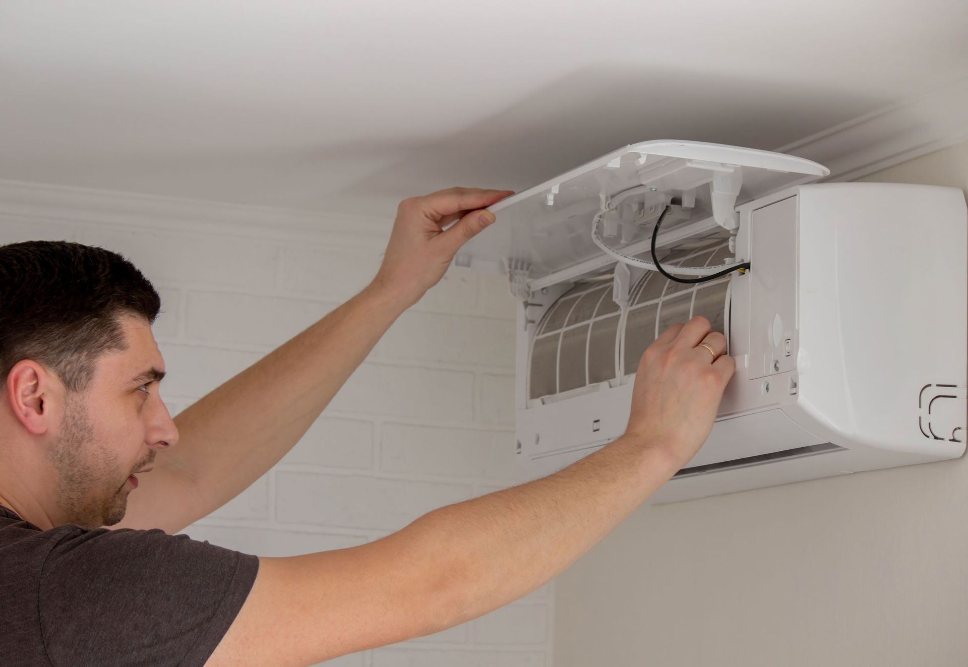 A man is cleaning the filter of an air conditioner.
