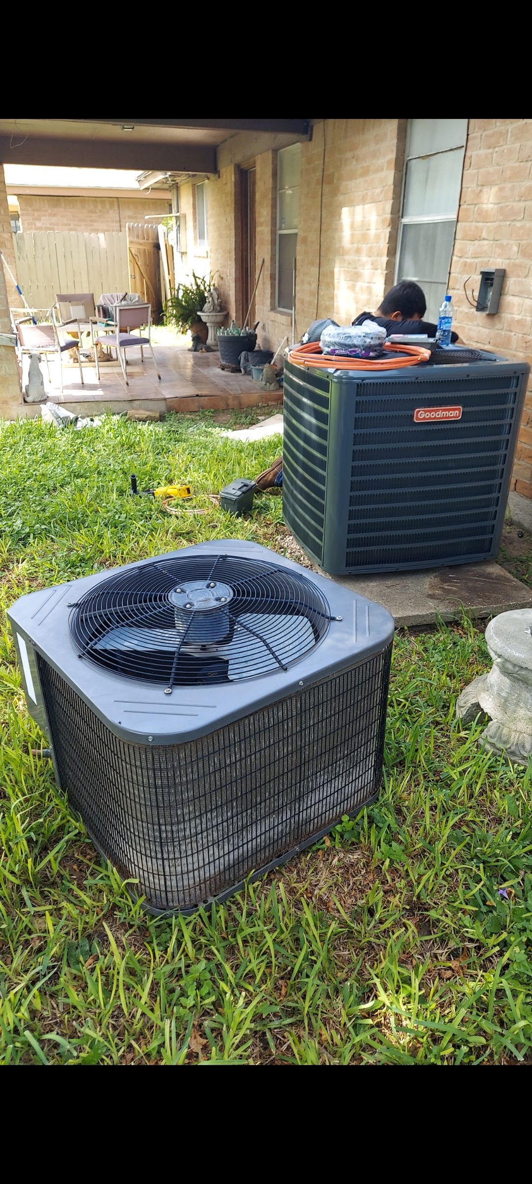 A row of air conditioners are sitting outside of a house.