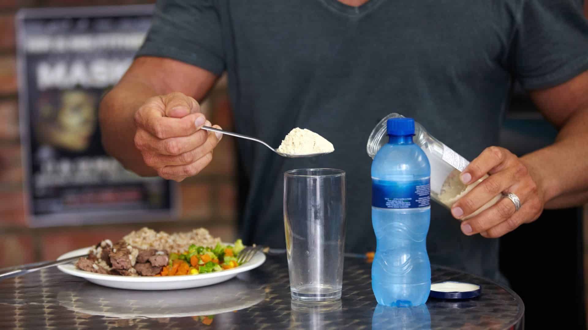 Man preparing a protein shake alongside a healthy meal, showcasing Prodigy Gym’s focus on nutrition and muscle recovery.