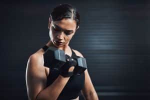 A woman is lifting a dumbbell in a gym.