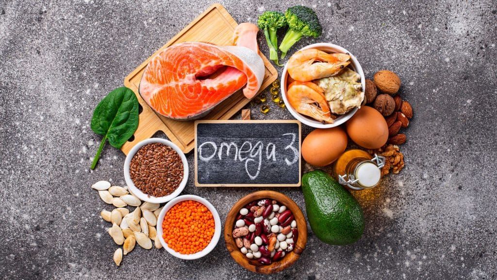 A variety of foods containing omega 3 are arranged in a circle on a table.