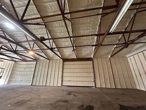 Interior view of a warehouse with spray foam insulation on the walls and ceiling, providing thermal protection.