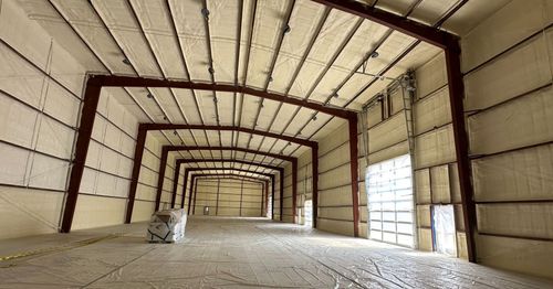 Interior of a large warehouse with brown metal framing and spray foam insulation, empty.