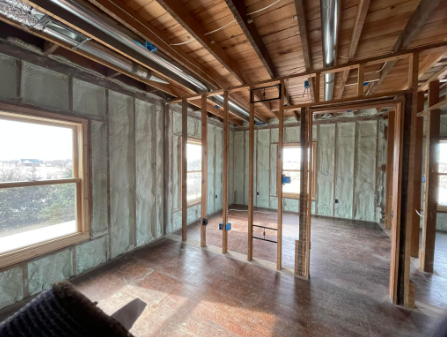 Interior of a room under construction, wood framing and insulation visible.