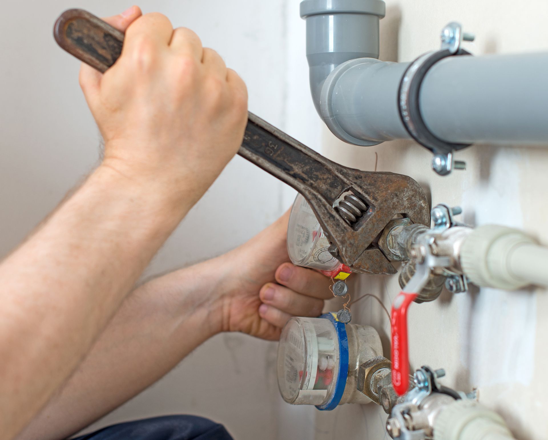 A man is fixing a pipe with a wrench.