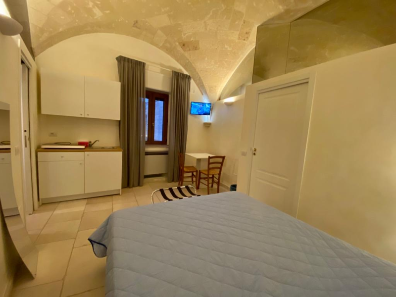 Una camera da letto con un letto, sedie, un tavolo e una televisione.