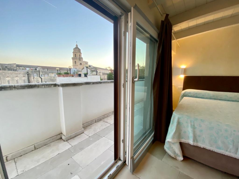 Una camera da letto con un letto e un balcone con vista sulla città