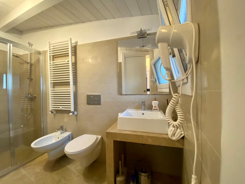 Un bagno con lavandino, water, bidet e doccia.