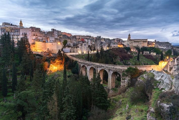 una città con un ponte in cima a una collina circondata da alberi .