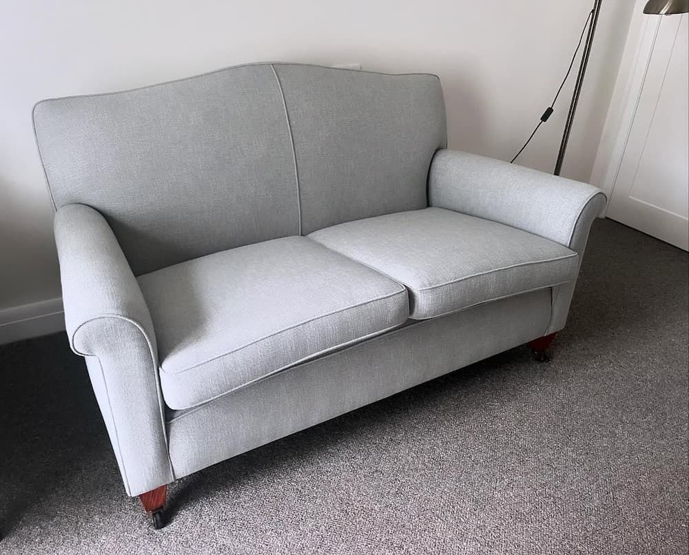 A grey couch is sitting on a carpeted floor in a living room — Metreson Upholstery In Unanderra, NSW
