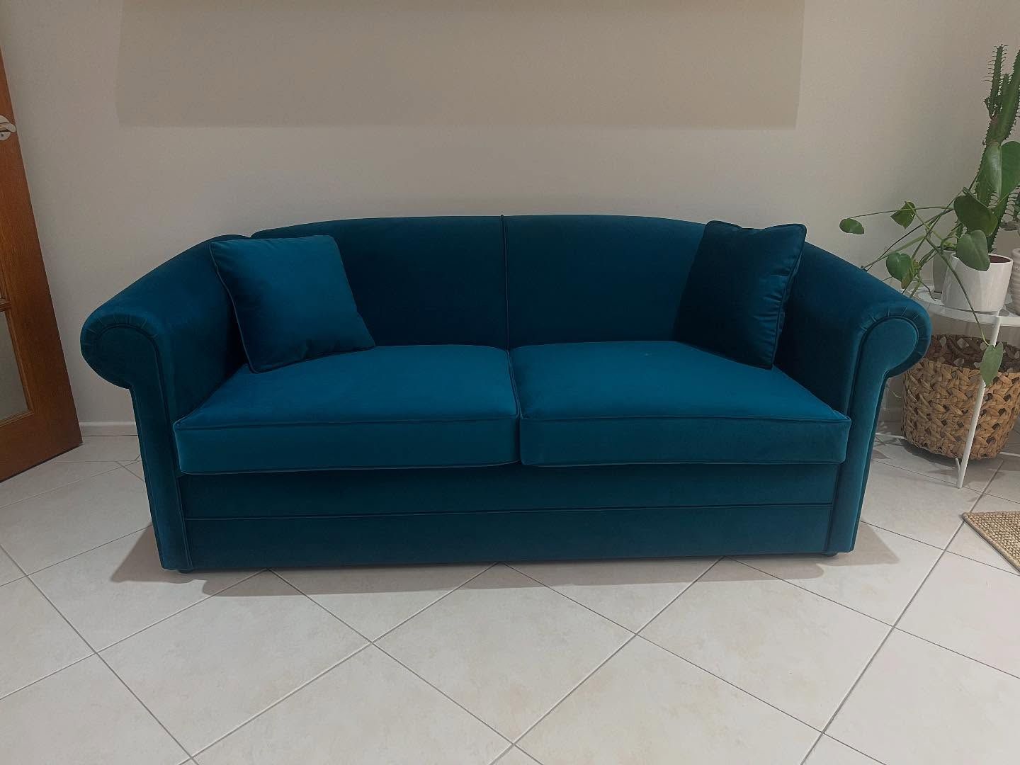 A blue couch is sitting on a tiled floor in a living room — Metreson Upholstery In Unanderra, NSW