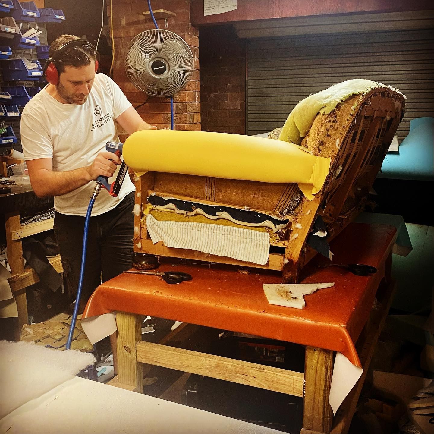 A man is working on a chair in a workshop — Metreson Upholstery In Unanderra, NSW