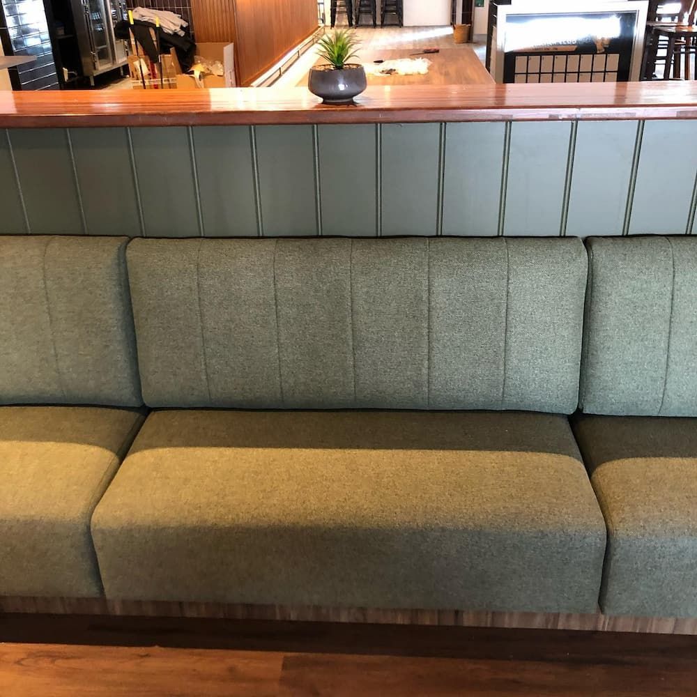 A couch in a restaurant with a plant on the counter — Metreson Upholstery In Unanderra, NSW