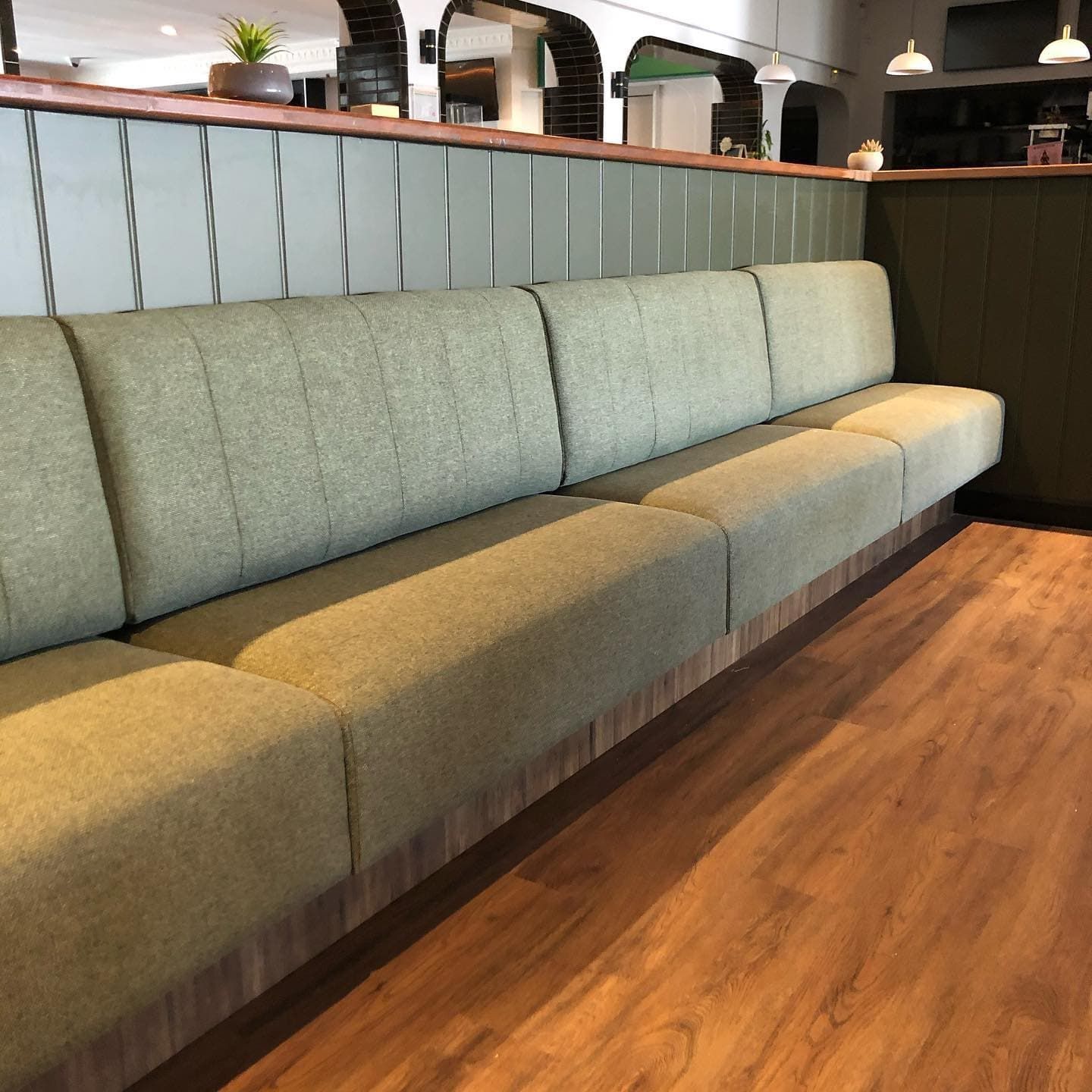 A long couch in a restaurant with a wooden floor — Metreson Upholstery In Unanderra, NSW