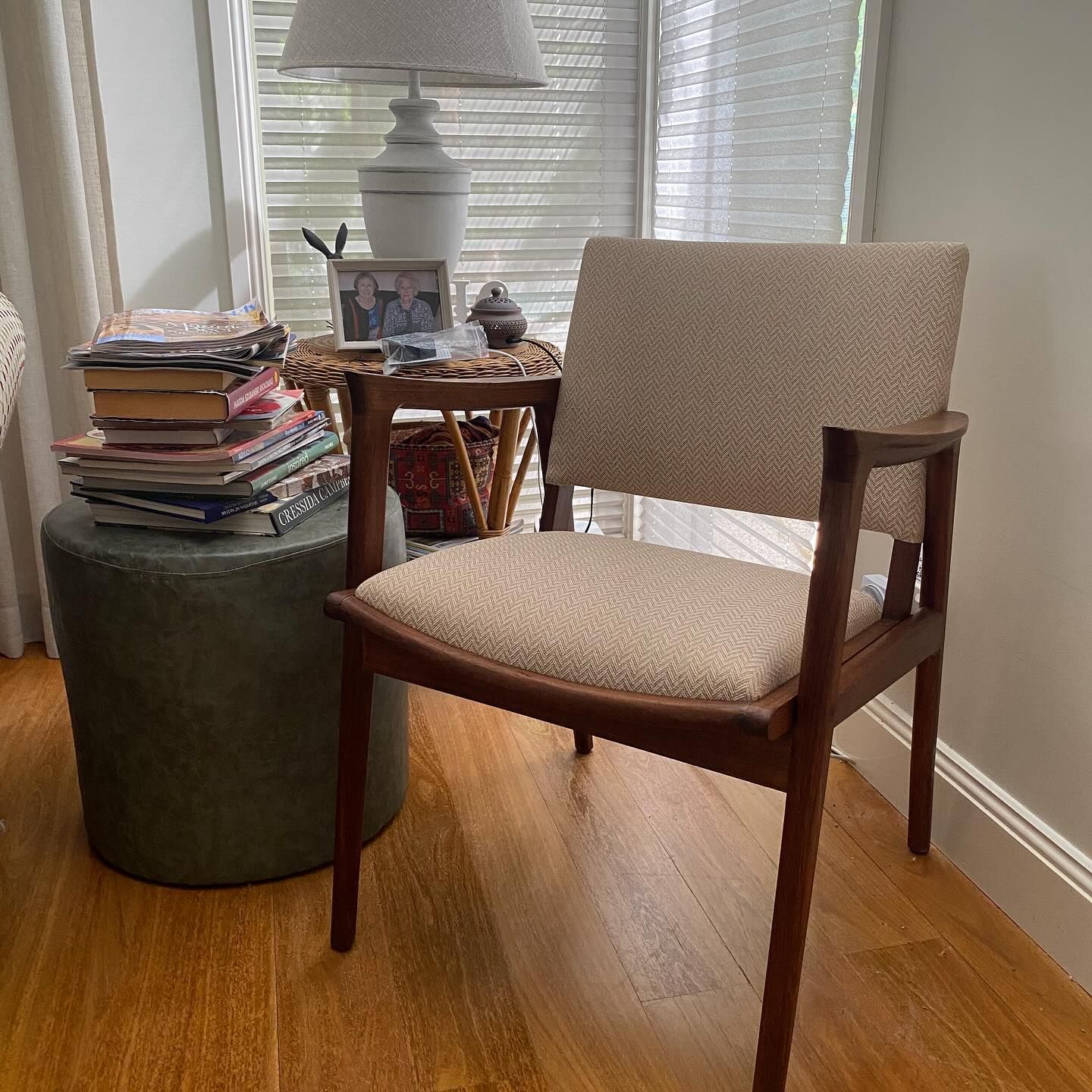 Chair with cream upholstery and wooden frame beside a small table and green ottoman next to a window.— Metreson Upholstery In Unanderra, NSW