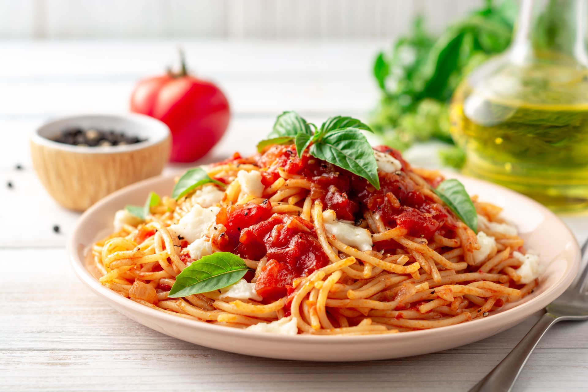A plate of spaghetti with tomato sauce and basil on a table.