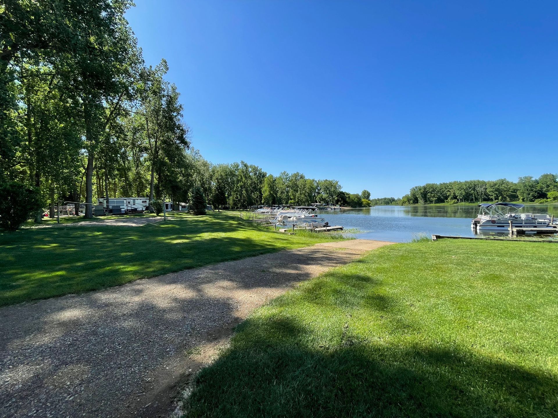 A path leading to a lake surrounded by trees and grass.