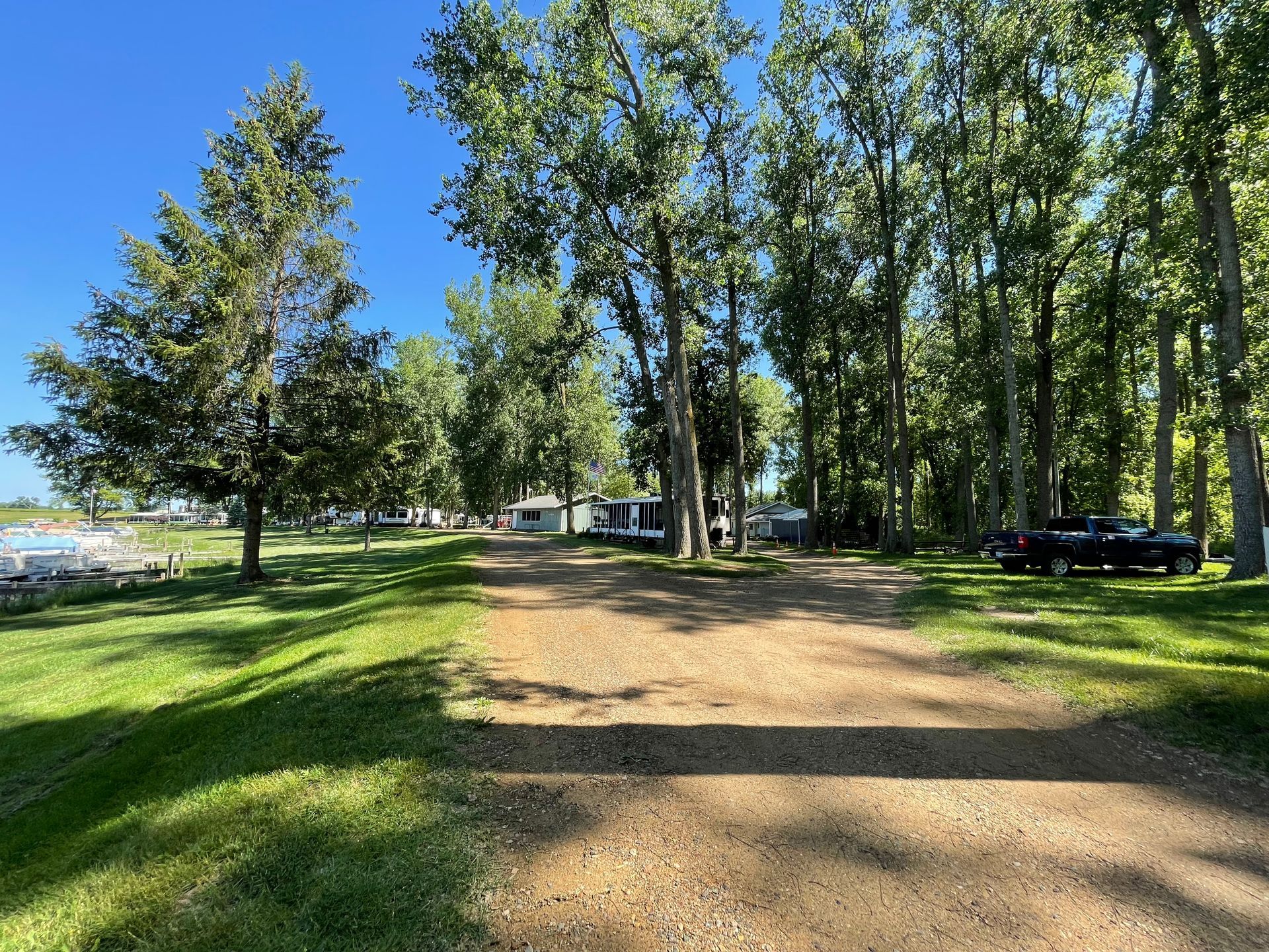 A dirt road leading to a campground surrounded by trees and grass.