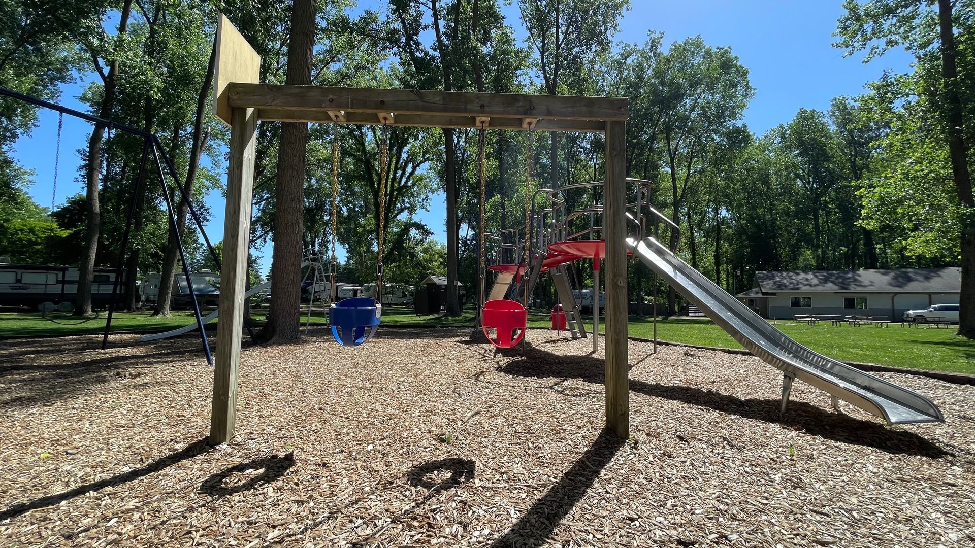 A playground with swings and a slide in a park.