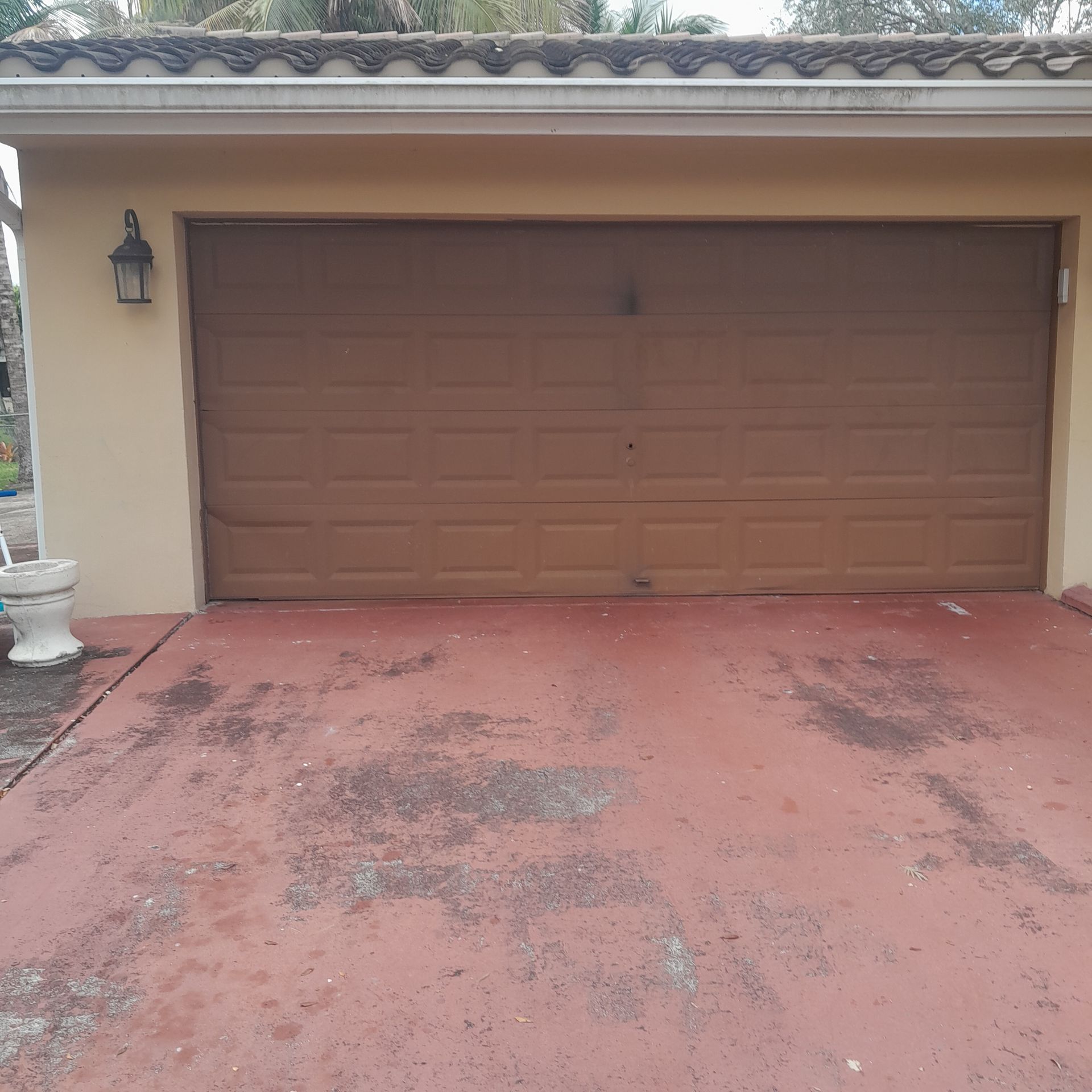 Brown garage door in a beige building with red concrete driveway in Parkland FL