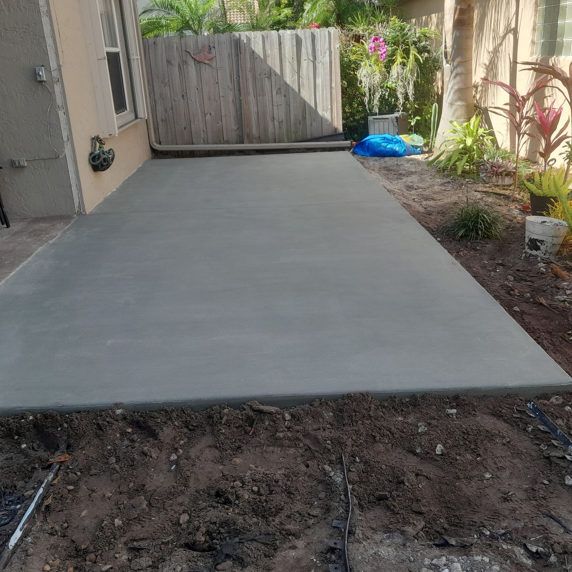 Freshly poured concrete patio with a wooden fence in the background in Parkland FL