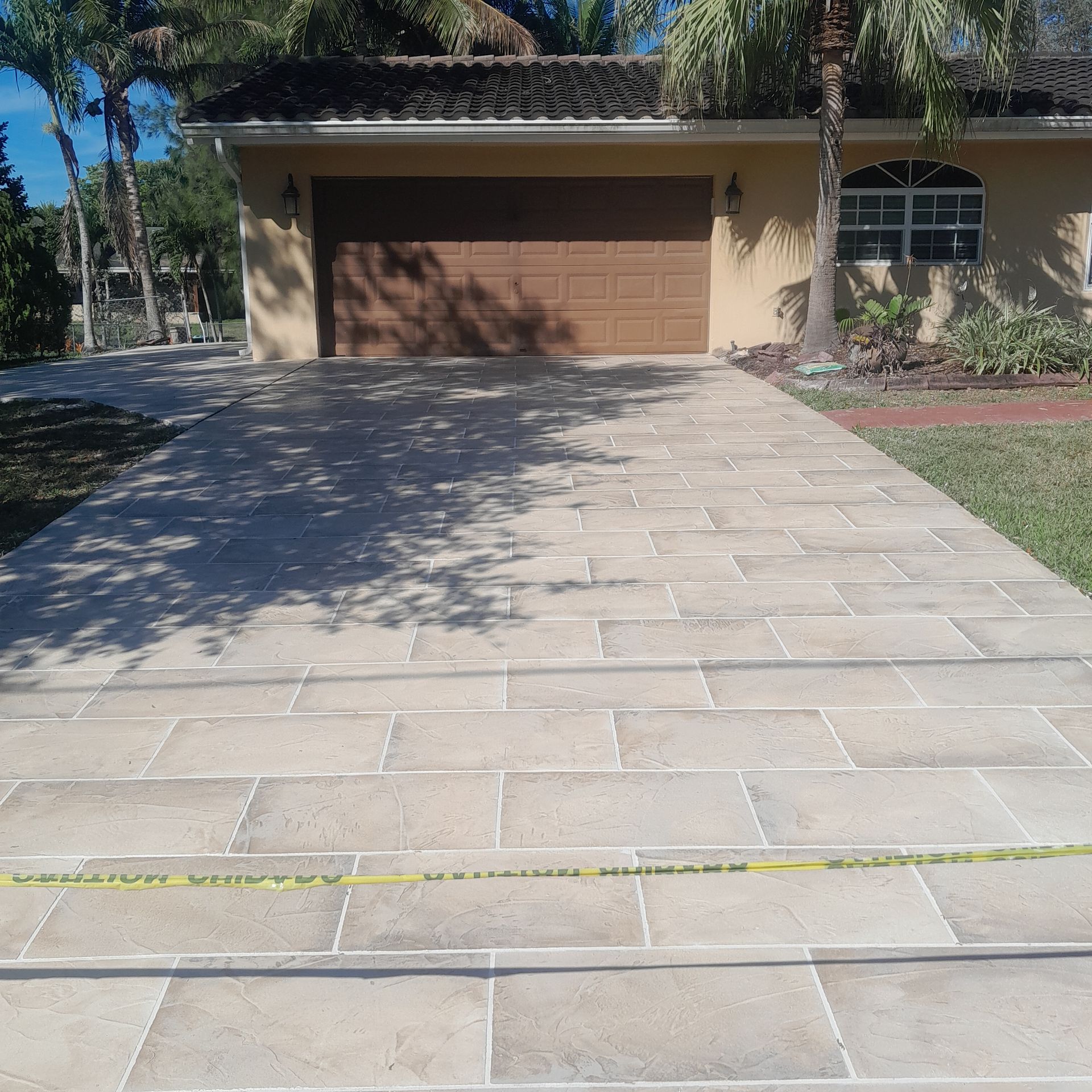 Driveway paved with light-colored rectangular stones leading to a garage door in Parkland FL