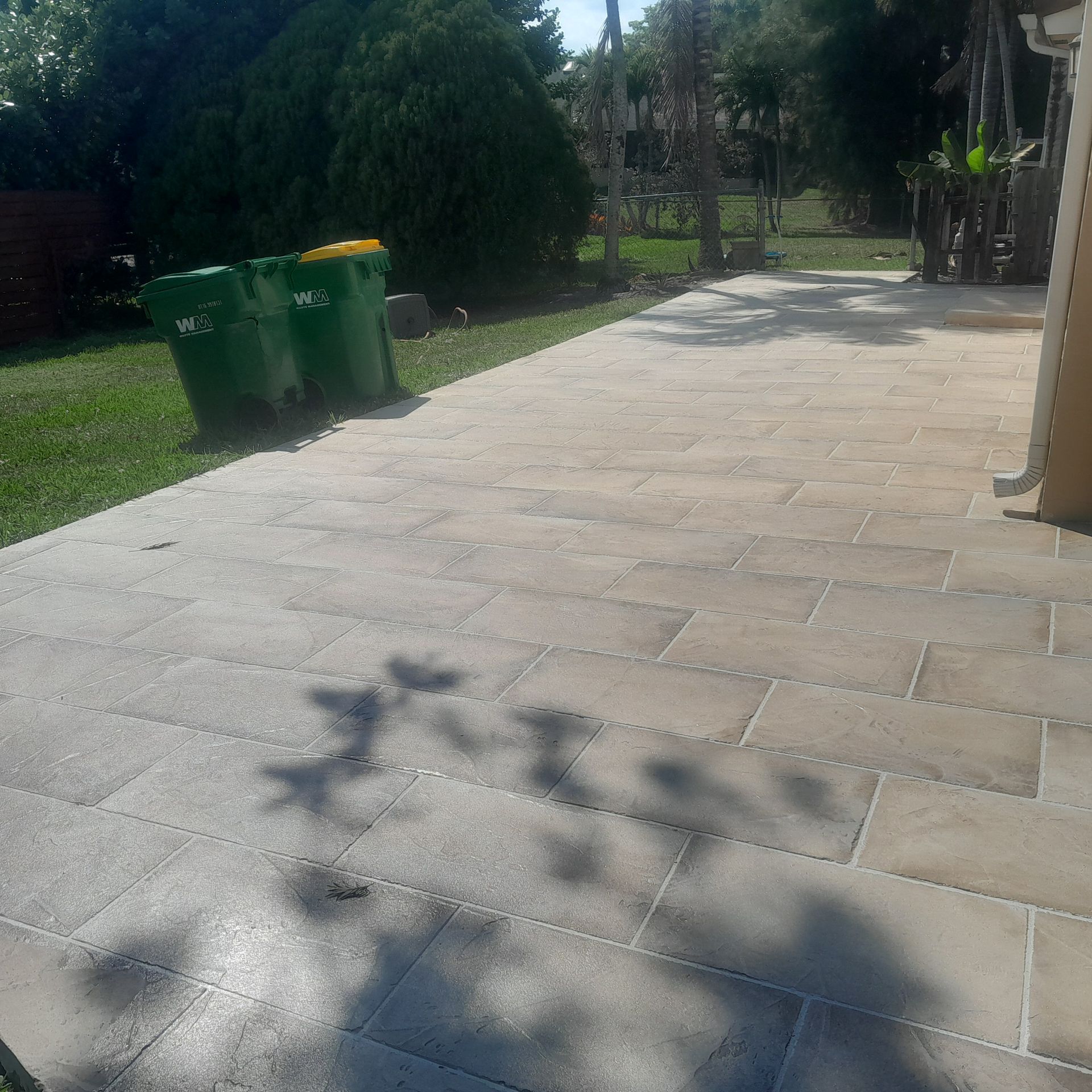 Paved patio with trash bins on the left, grassy area in Parkland FL