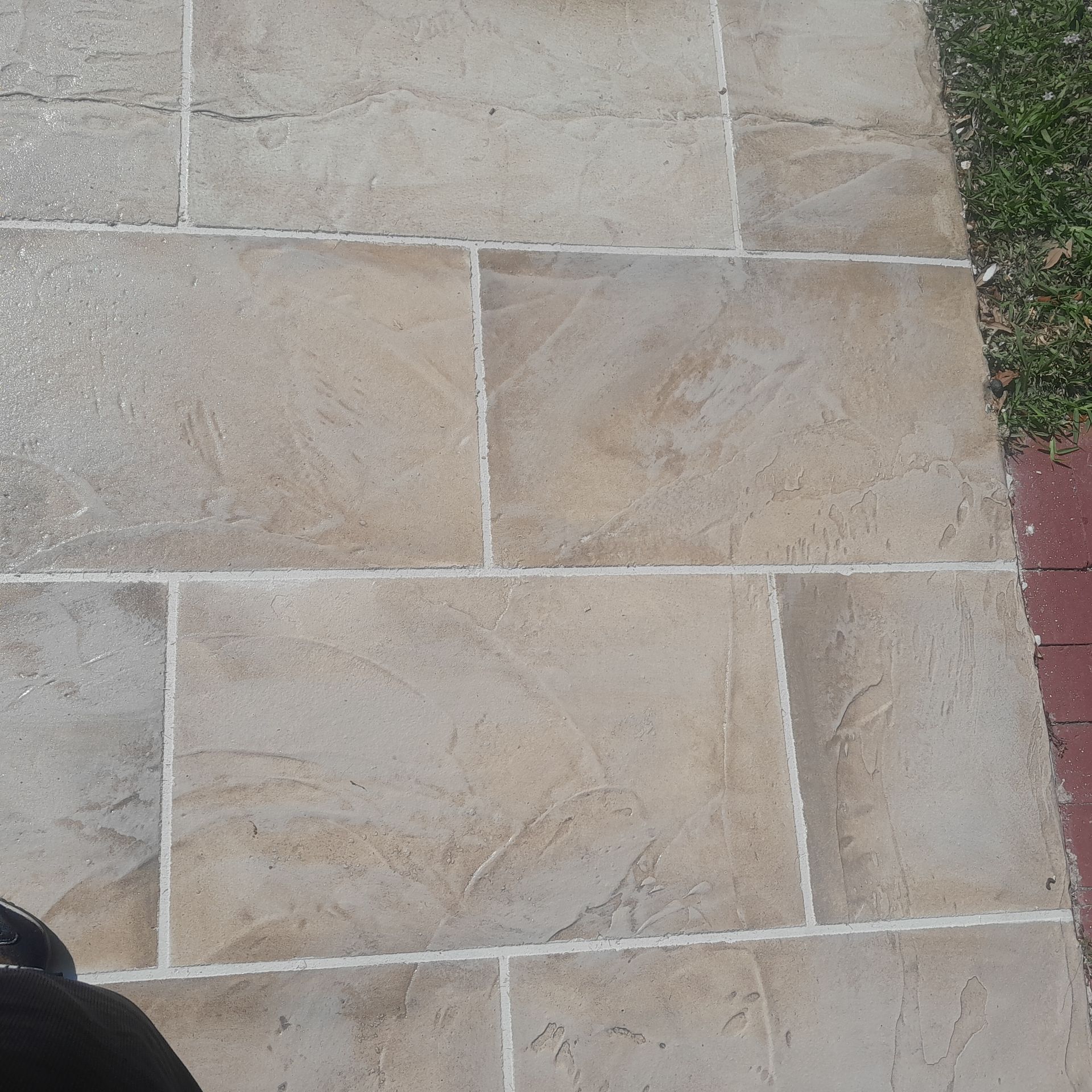 Beige rectangular paving stones with white grout, next to grass and red bricks in Parkland FL